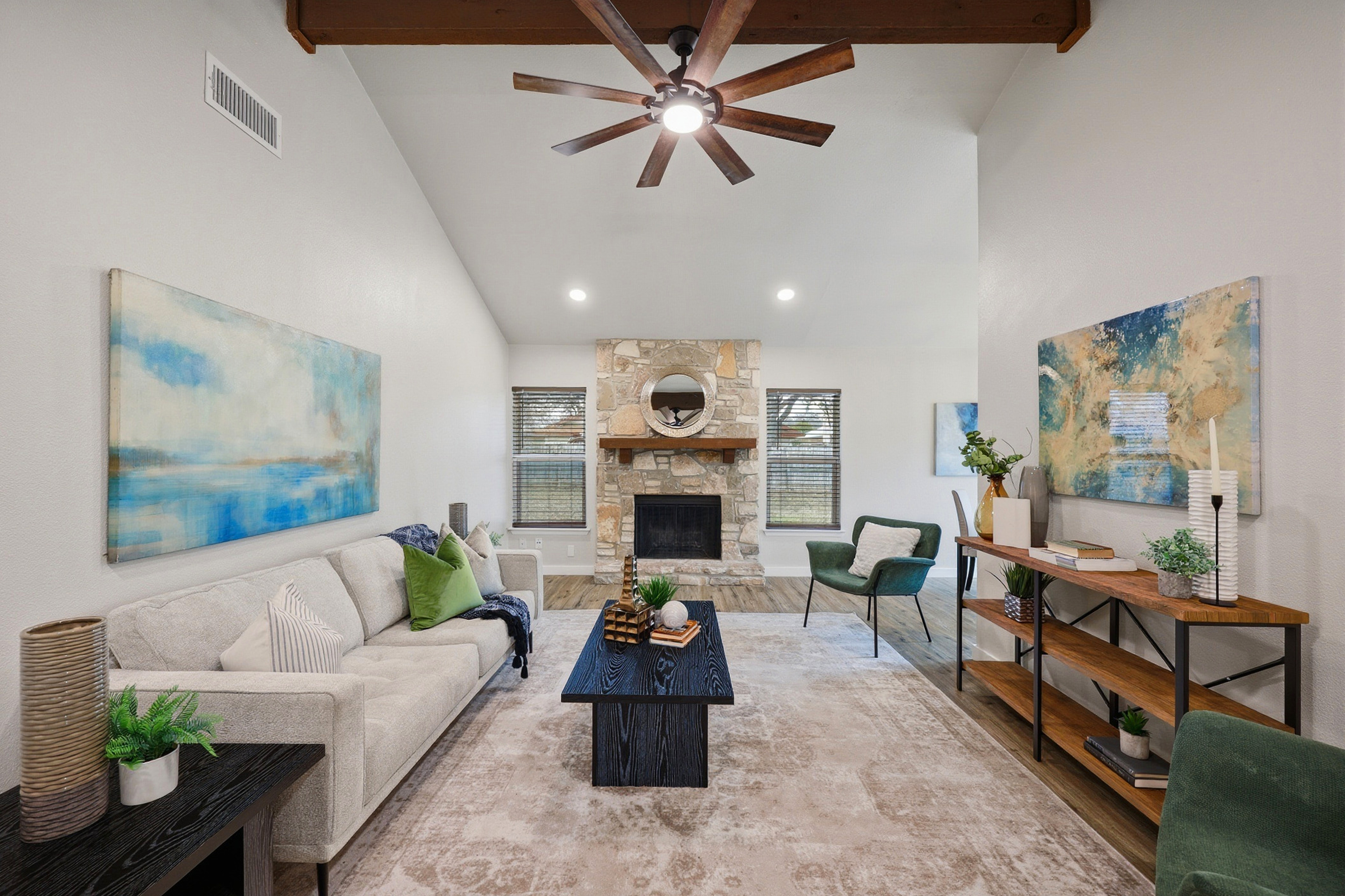 Vaulted family room with exposed wood beams, stone fireplace, and ceiling fan at 8247 Lewiston St